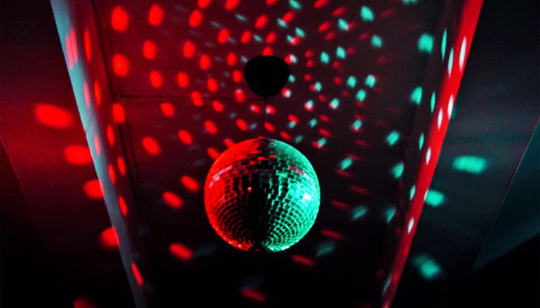 The image shows a disco ball in red and green light. (light-trapping crystal concept)
