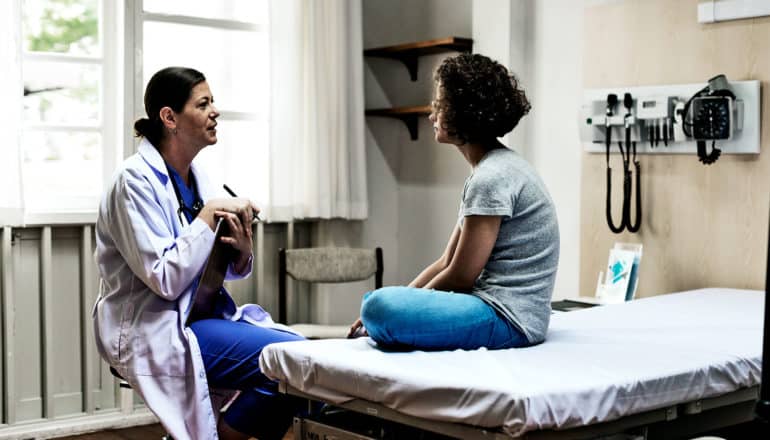 The image shows a doctor and patient talking in the doctor's office.