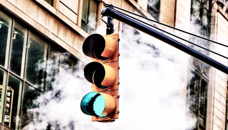 green traffic light hangs in front of puff of smoke
