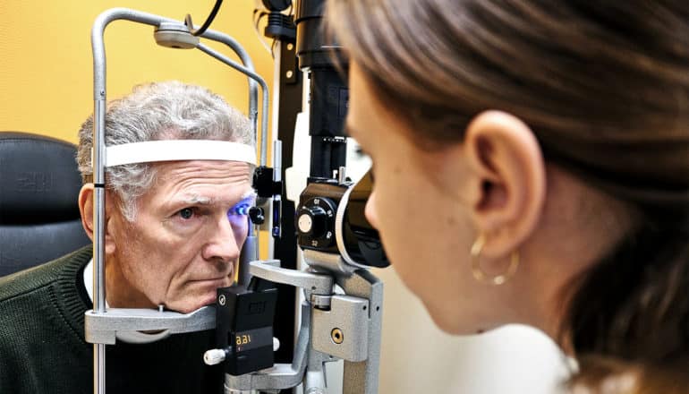 The image shows a man getting an eye exam. (vision impairment concept)