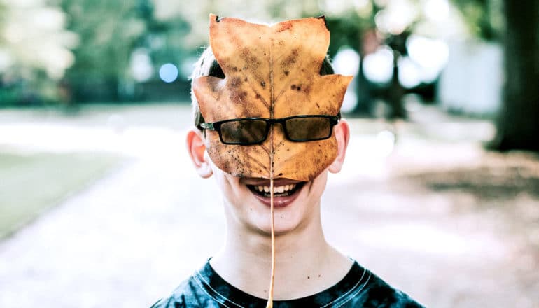 boy with a yellow leaf beneath his glasses over his face to suggest growth mindset