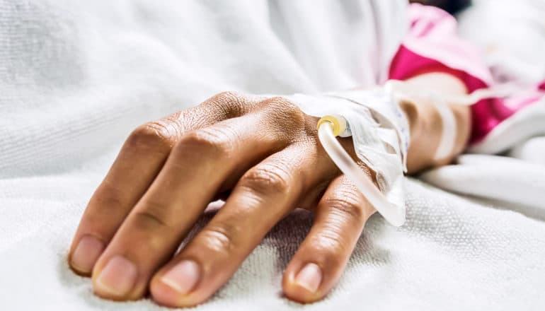 The image shows a hand with an IV in it. (intravenous antibiotics concept)