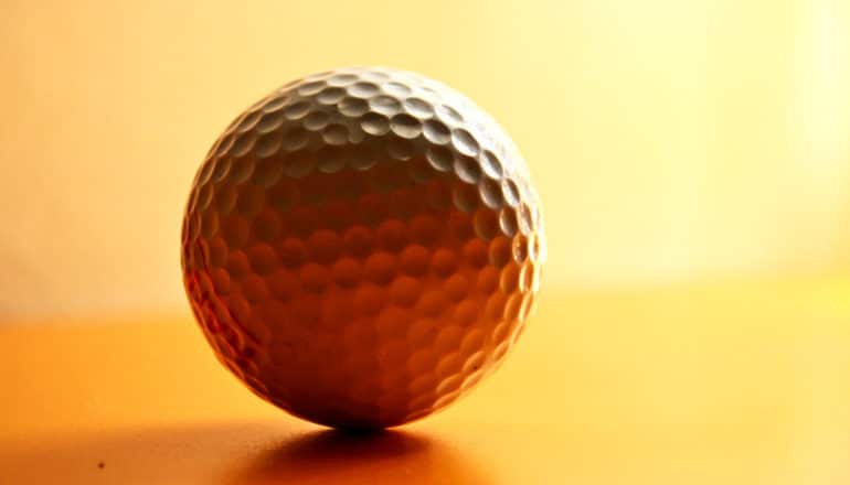 orange light from behind leaves front of golf ball in shadow