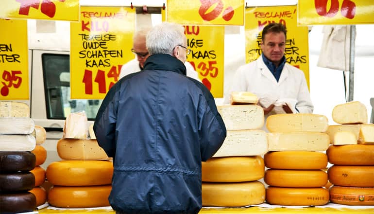 The image shows a man in a dark jacket looking over a cheese stand. (gas chromatography concept)