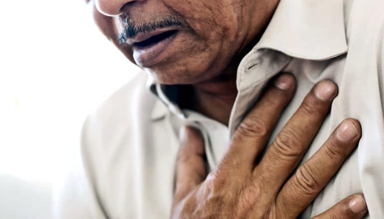 a man holds his hand over his chest as he struggles to breathe.
