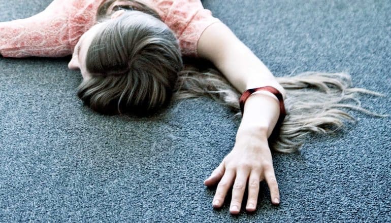 woman face down on floor with arm outstretched