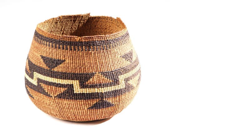 woven basket with irregular edge on top and geometric design in shades of brown and beige