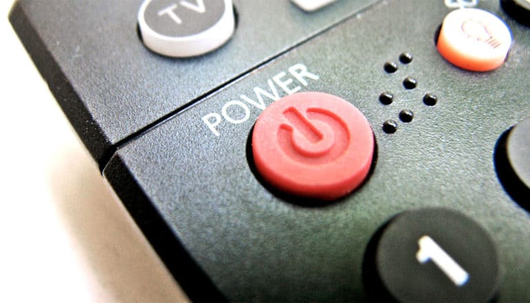 The image shows a red power button on a television remote (sodium-ion batteries concept)