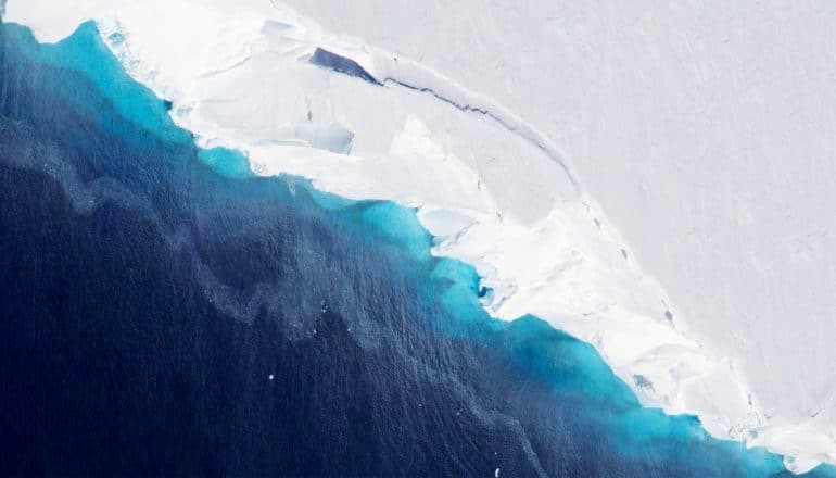 The snow-covered Thwaites Glacier meets the deep blue ocean
