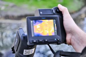 A researcher holds a thermal camera showing an image of an alligator