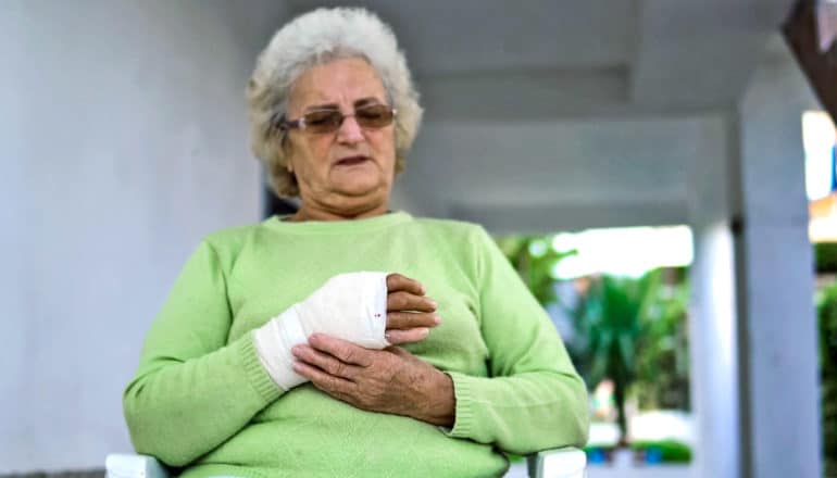 older person massages wrist in cast
