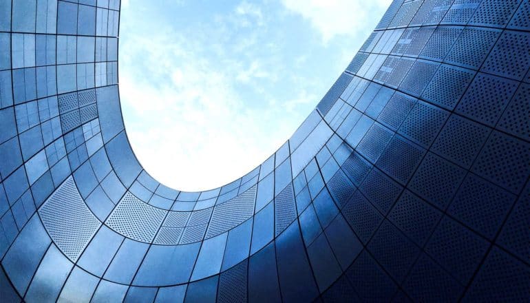 A curved part of a highrise building shows up blue with the light from the blue sky