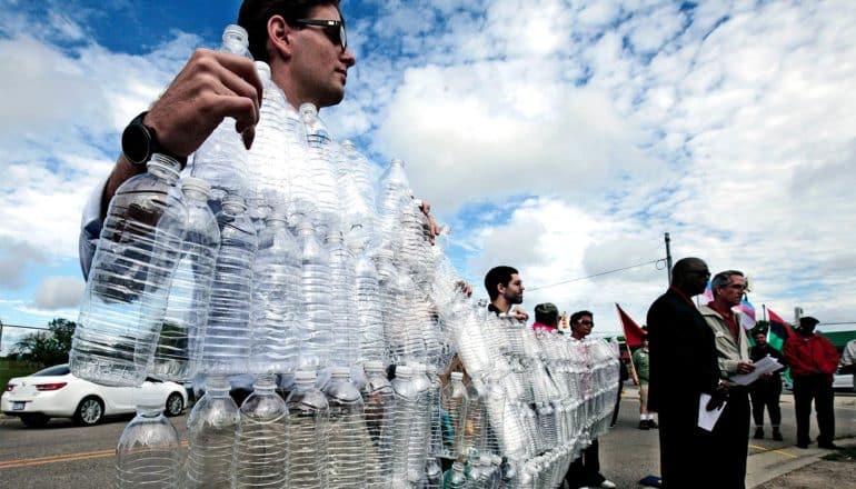 protestors hold up a banner of connected water bottles