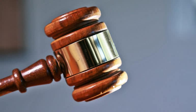 A gavel falls against a blue background
