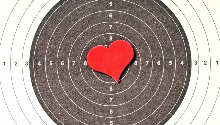 A red heart-shaped cut-out sits on a black and white target