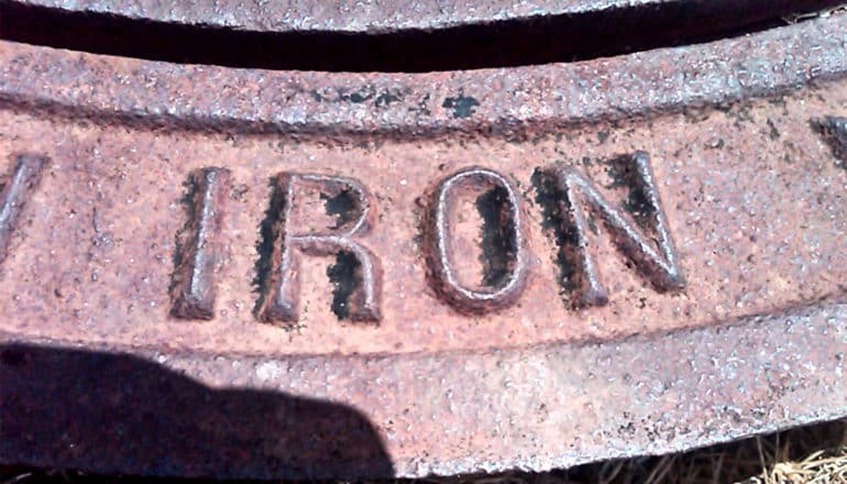 The word "iron" is embossed on a piece of rusting iron