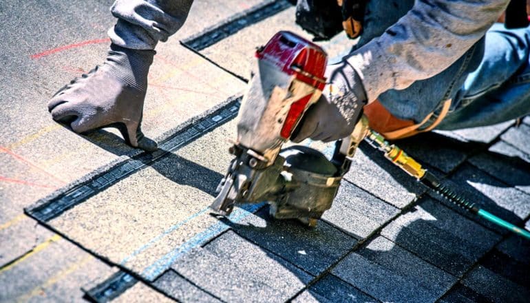 person fires nail gun into roof shingles