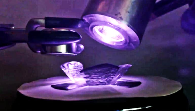 A robotic "flower" sits under a purple light with a mechanical arm to the left