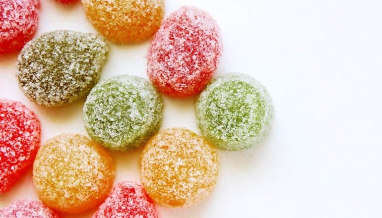 Chewy, colorful candies covered in sugar sit on a white background