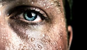 A sweaty man looks at the camera, the shot close-up on his eye