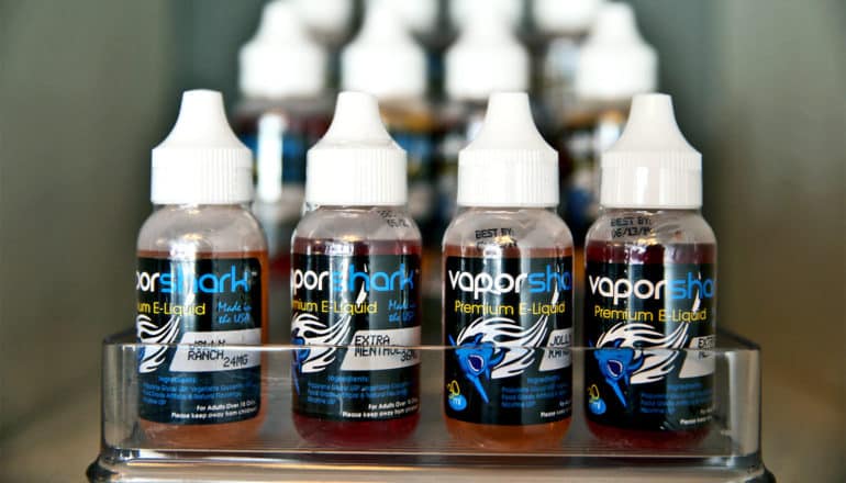 Small bottles filled with vaping liquid sit in rows of four