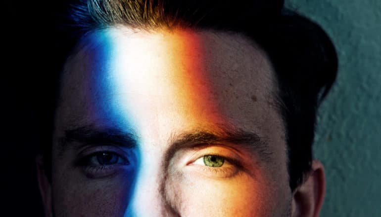 A man's face with colored light shining on it