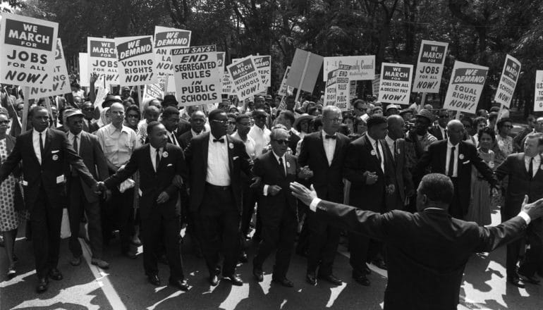 crowd of people hold signs in support of voting rights and desegregation