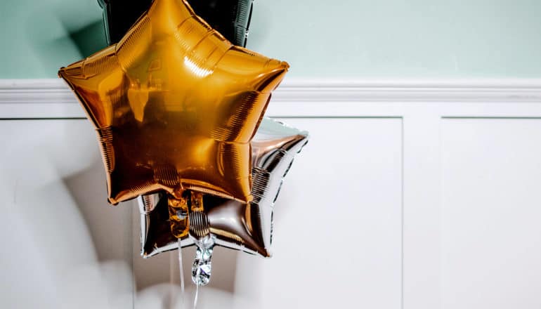 Three star balloons float in a white and green room