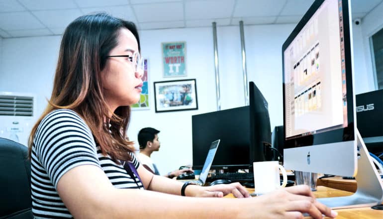 A woman sits at her computer desk in an office