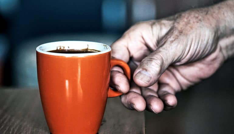 A man reaches for a bright orange coffee cup