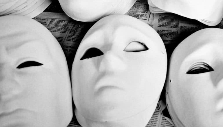 A set of unpainted masks sit on a newspaper