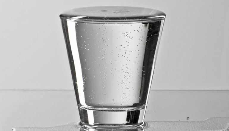 water brims over the top of a glass