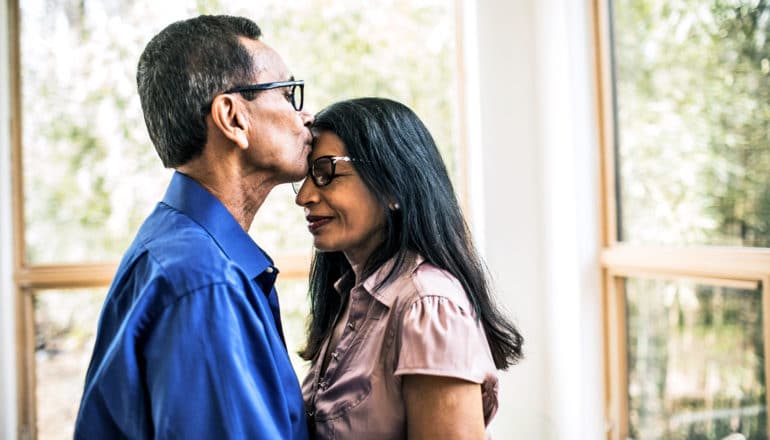 middle-aged man kisses woman on forehead