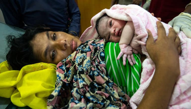 woman stares away with newborn on chest