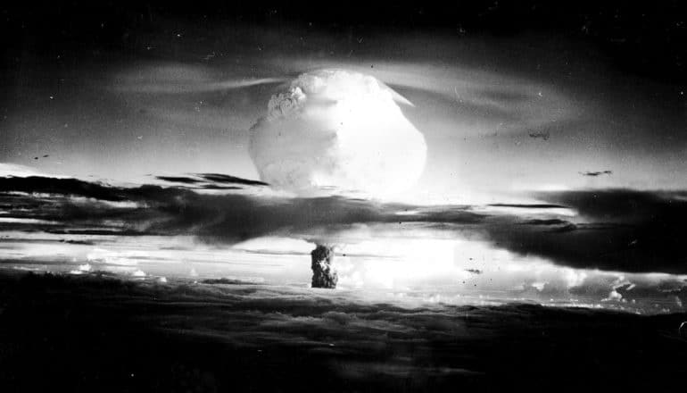 The mushroom cloud from a nuclear blast pierces dark clouds