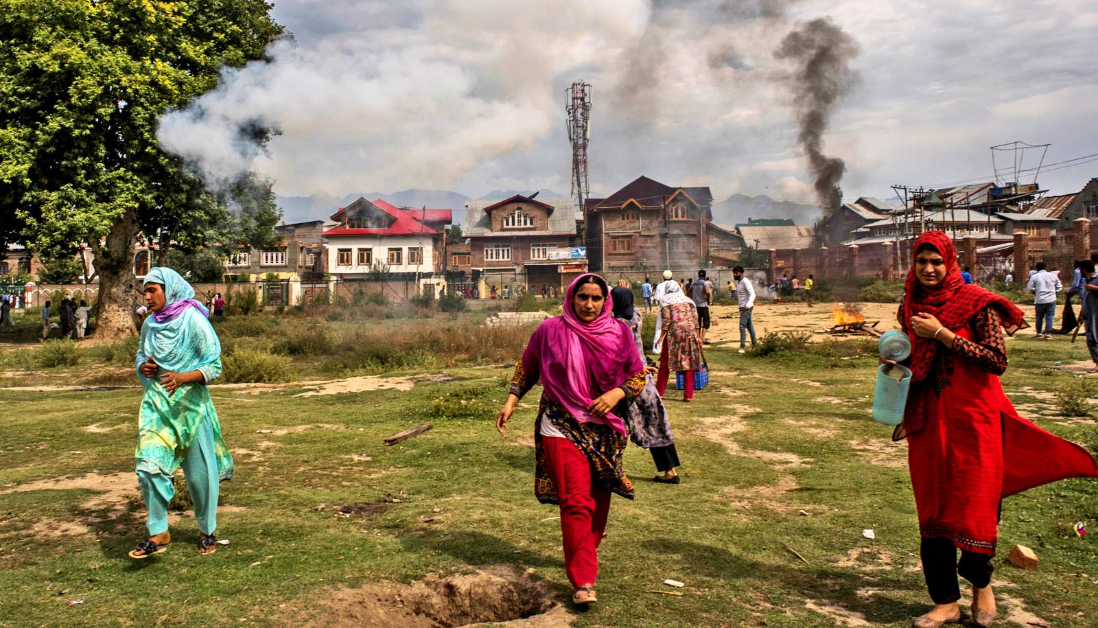 people hustle away from smoke over houses