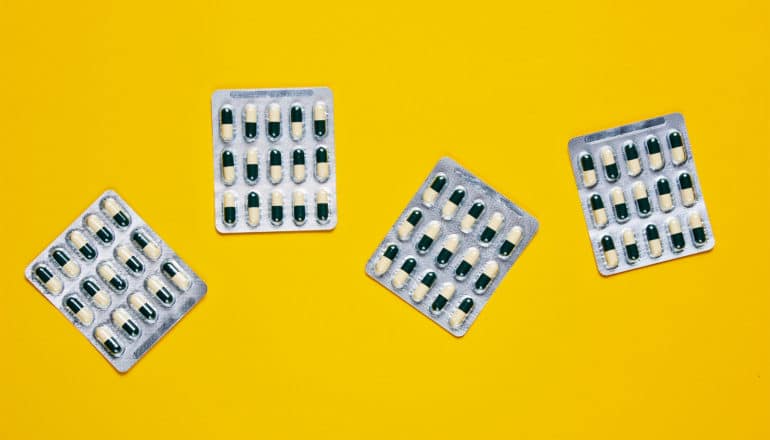 4 packs of pills sit on a yellow background