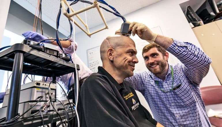 A researcher attaches electrodes to Chmielewski’s head as they both smile