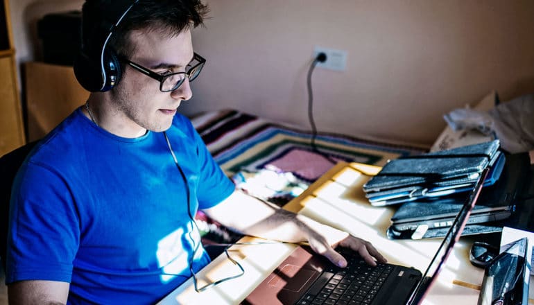 A man plays a game on his laptop while wearing headphones