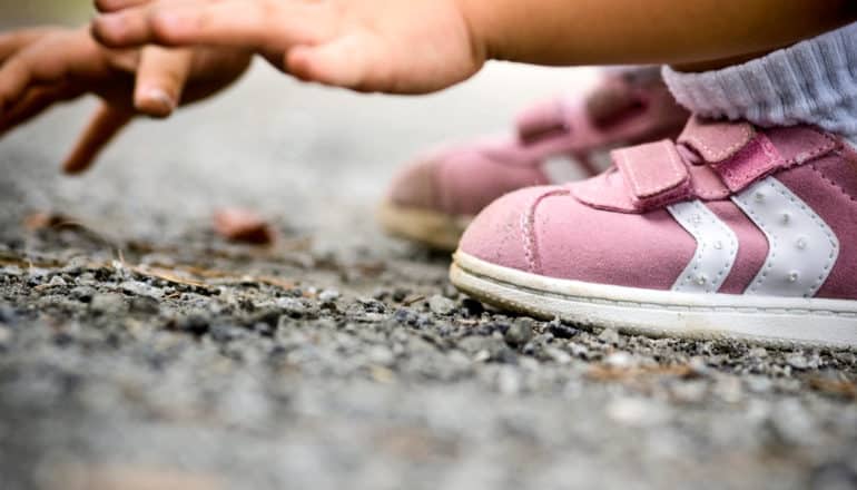 sneakers and hands of child squatting on the ground