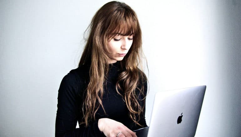 A woman uses her laptop against a gray background
