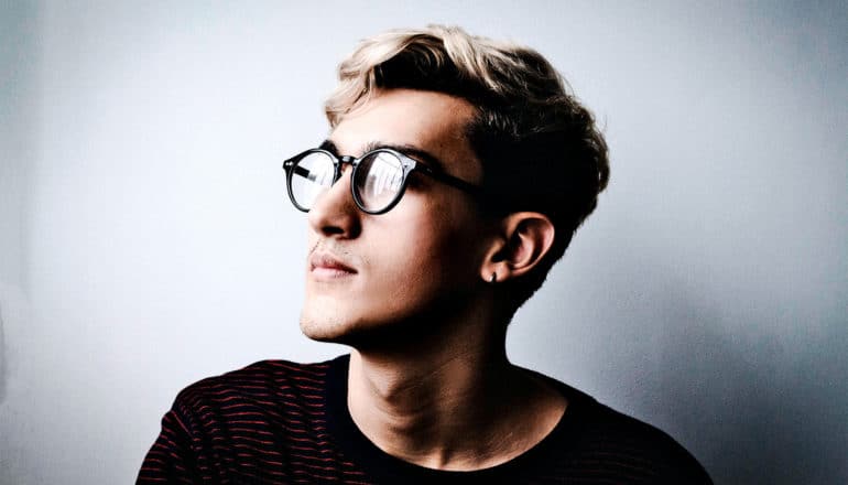 A person with glasses looks off camera, lost in thought