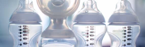 four baby bottles, one attached to breast pump flange
