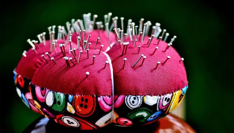 A red pin cushion with many pins in it