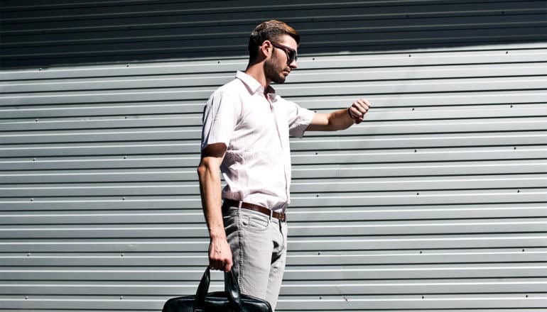 A man checks his watch while holding a briefcase