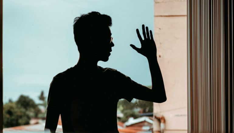 person in silhouette waves hand