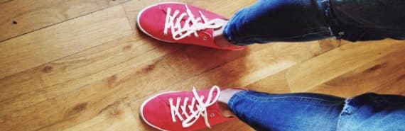 looking down at legs in jeans and feet in red sneakers