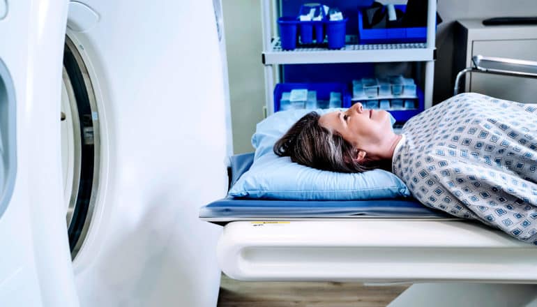 A woman waits for an MRI while lying on an an exam table