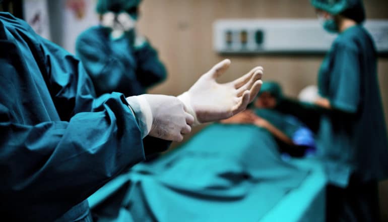 surgeon puts on glove in operating room