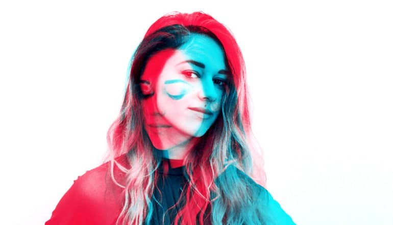 A double exposure photo of a young woman shows her making a serious face and looking down in red and a more optimistic, positive face in blue